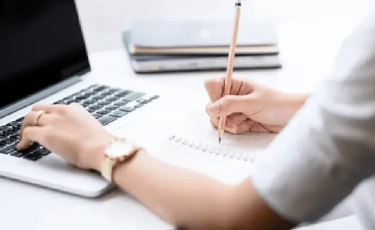 パソコンを操作しながらメモをしている写真